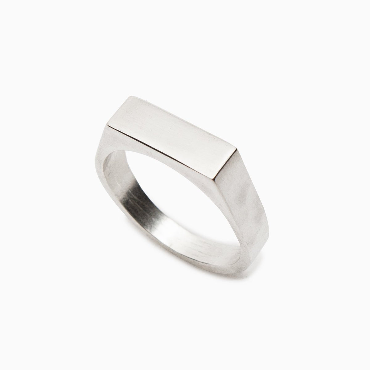 A narrow signet ring with a polished rectangular top and hammered detail on the band. Made in solid sterling silver. Designed and handcrafted in Portland, Oregon.