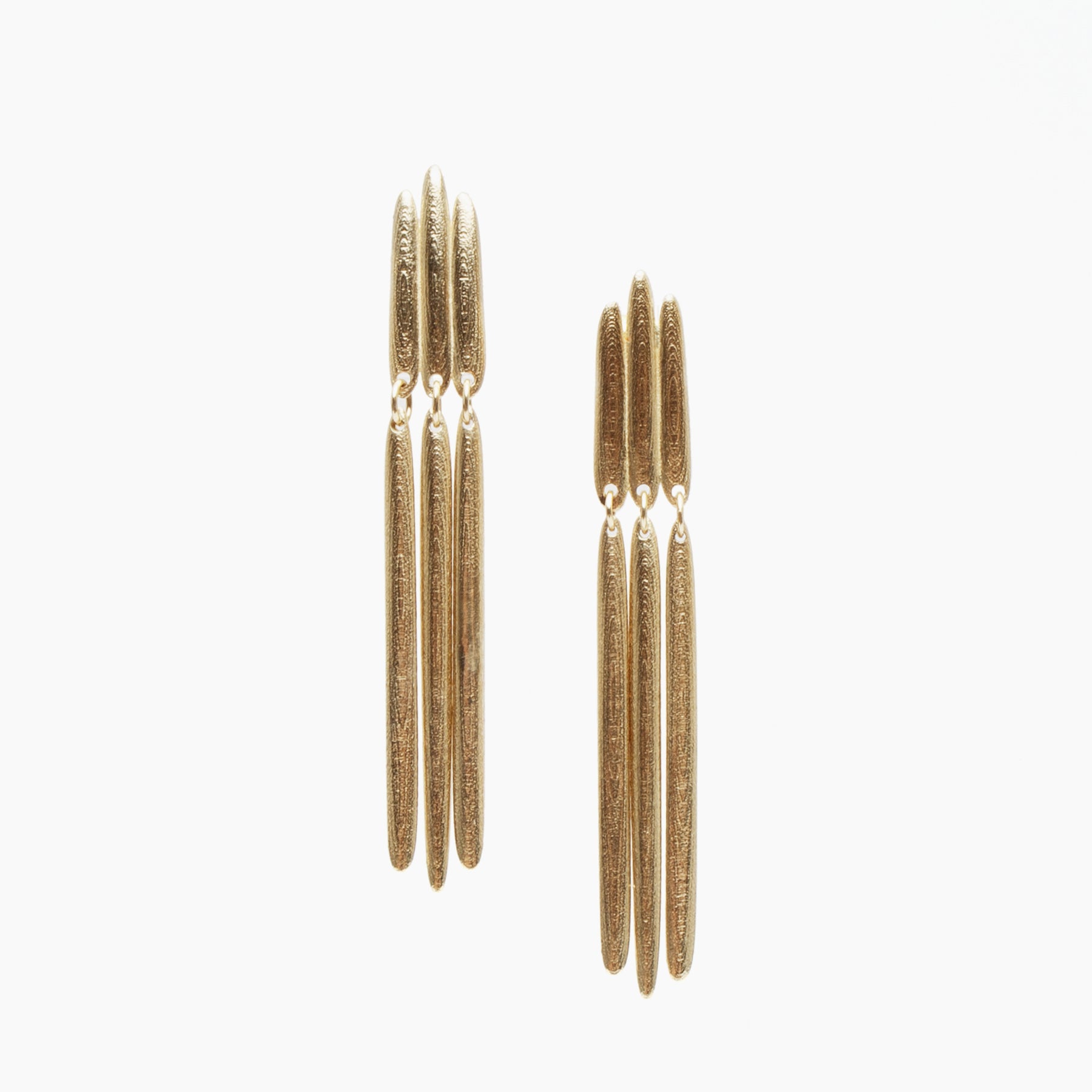 14k yellow gold earrings by Portland jewelry designer Betsy & Iya for Fiina featuring three organically shaped cylinders near the ear and three dangling cylinders hanging below.