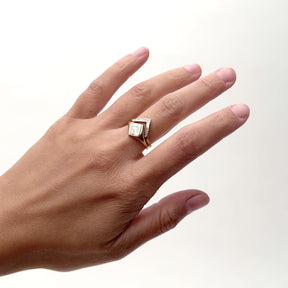 A model wears a V-shaped Altus 14K recycled gold stacking ring, with lab-grown diamonds on their middle finger. The V-shaped band is stacked with a square style signet ring that showcases a pattern of baguette diamonds. Designed and handcrafted in Portland, Oregon.