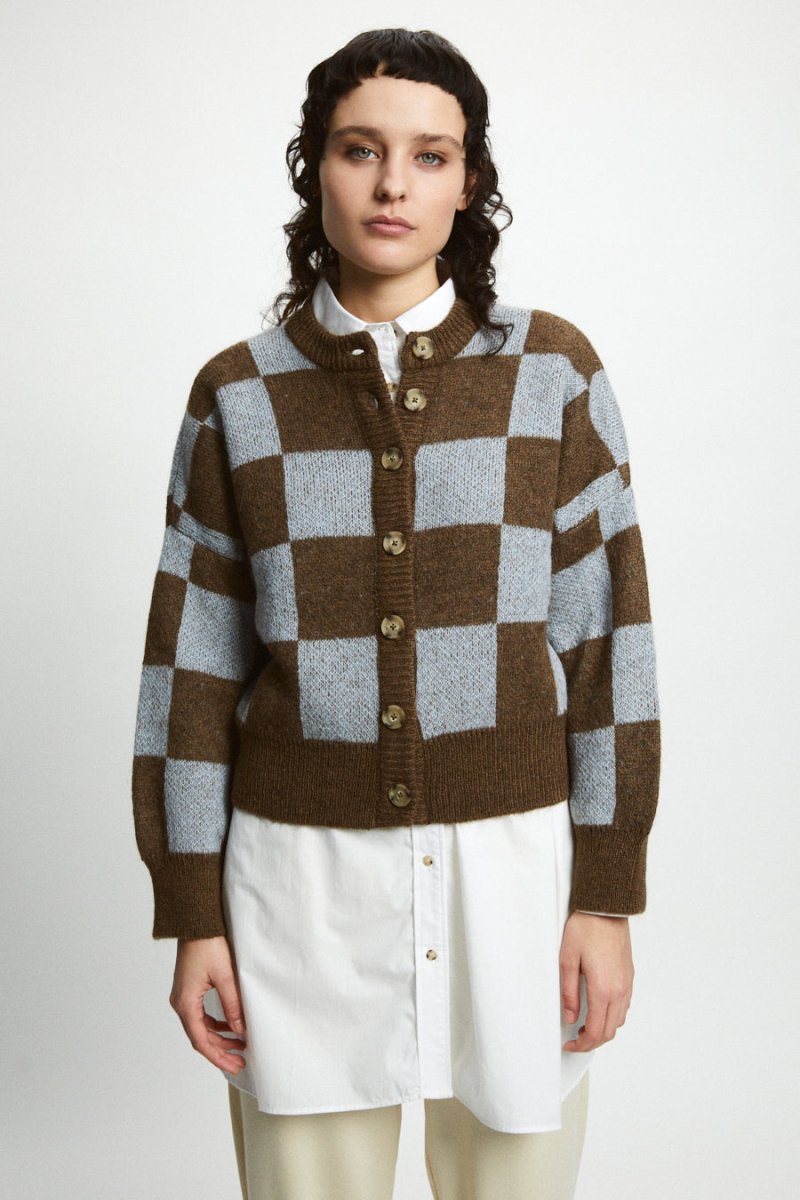 A model wears a knitted button up cardigan in a brown and light blue pattern. The Ellen Sweater in Brown + Blue is designed by Rita Row and made in Girona, Spain.