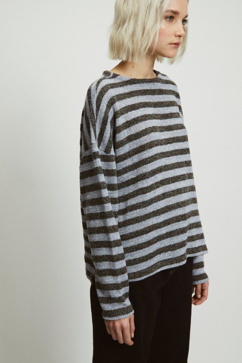 A model wears a light blue and dark ray striped sweater. The Etta Sweater in Stripes is designed by Rita Row and made in Girona, Spain.