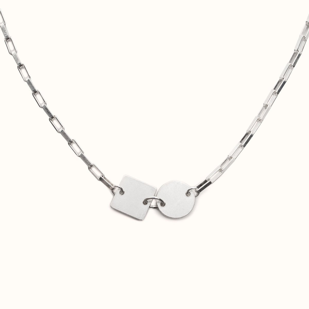 A sterling silver small link chain necklace with a flat square and flat circular focal piece. The Acreca Necklace is designed and handcrafted by Betsy & Iya in Portland, Oregon.