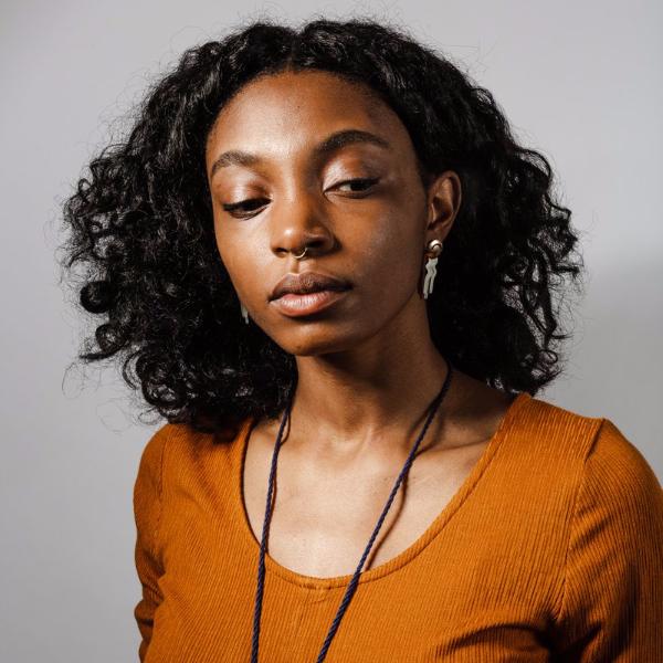 Lightweight, bronze, domed studs with wavy sterling silver fringe; worn on a model with curly black hair and an ochre dress.