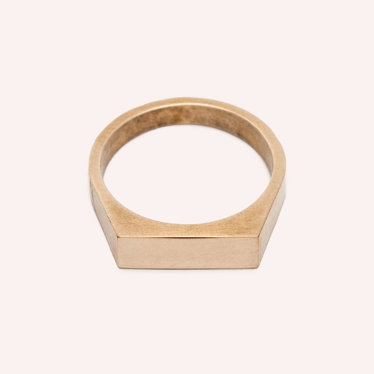 A narrow signet ring with a polished rectangular top and hammered detail on the band. Made in bronze. Designed and handcrafted in Portland, Oregon.