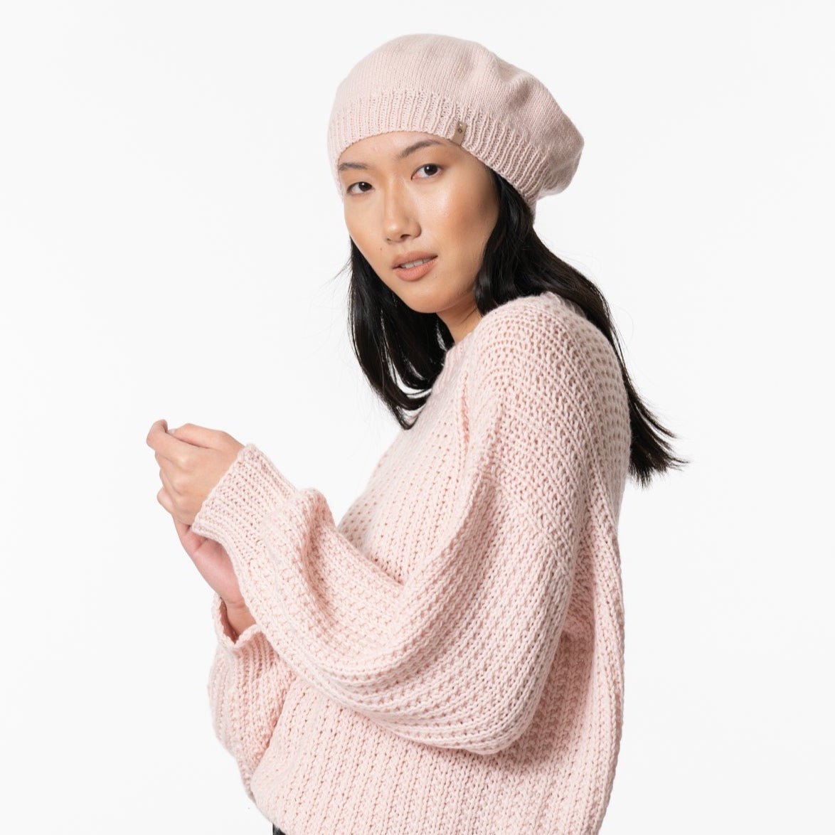 a model wears light pink beret. The Merino Handknit Beret in Blush pink is designed by Dinadi and hand knit in Nepal.