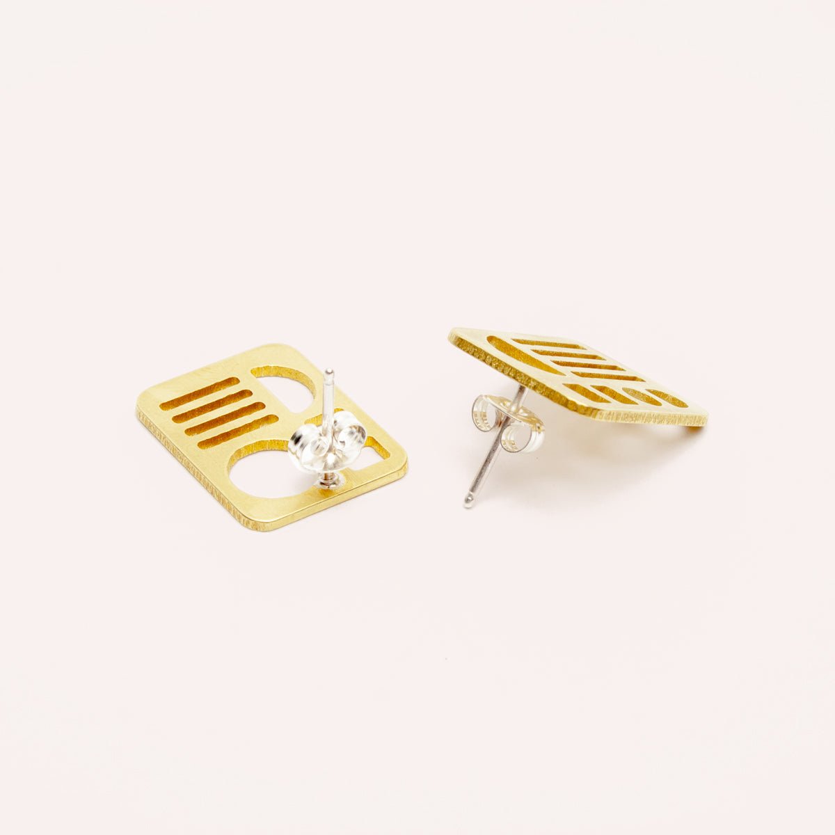 A small brass rectangular stud earring with circles, lines, squares and half moon cut outs. Designed and handcrafted in Portland, Oregon.