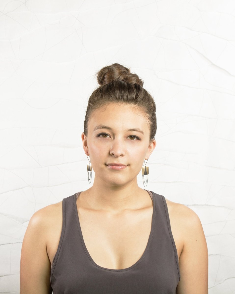 Model wears the dangly betsy & iya gold and black strata drip earrings to show scale.