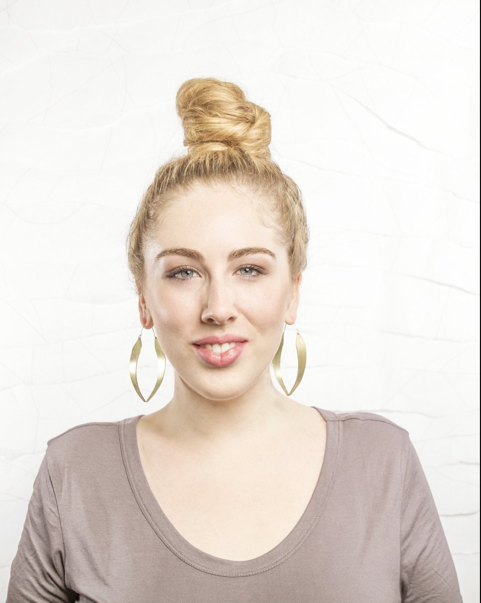 A woman wears the betsy & iya two captains hoops next to a simple background to show size of hoops.