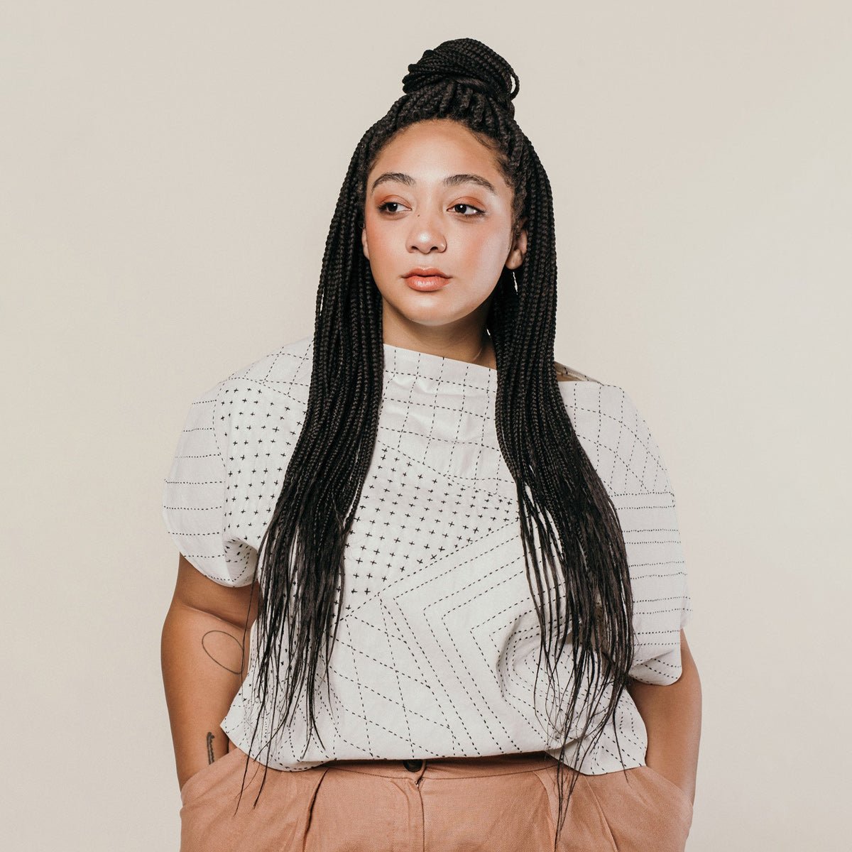 Model wears a short sleeve canvas cotton box top with a black hand embroidered pattern. The Box Top in Bone is designed by Anchal in Louisville, Kentucky and handmade in Ajmer, India.