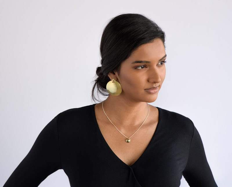 Caderas shield earrings in brass on model