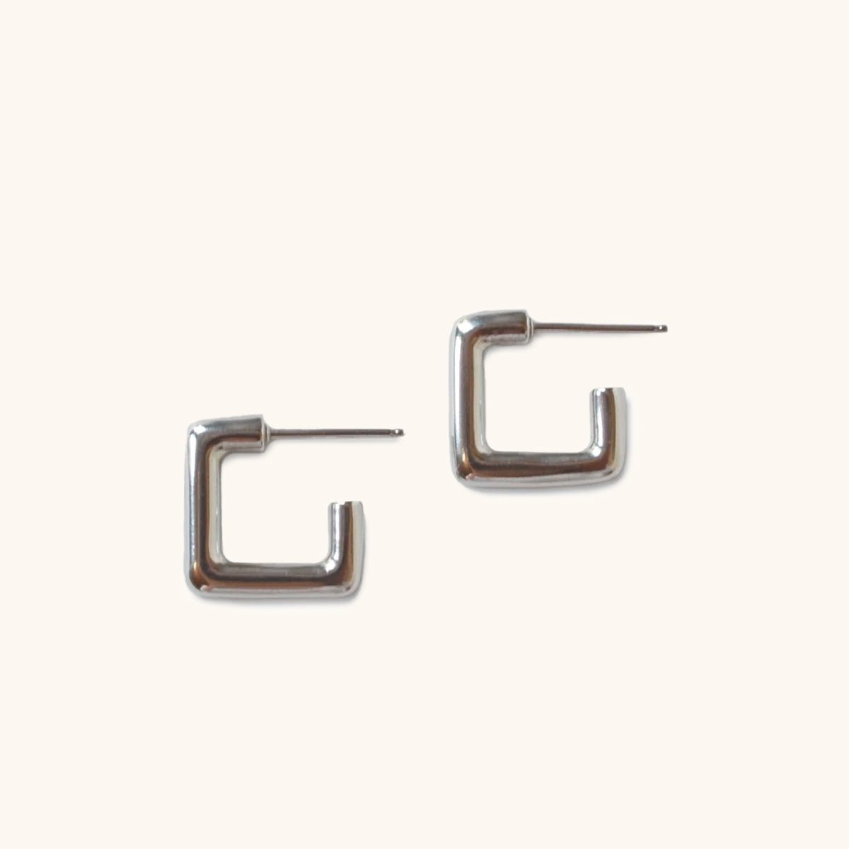 A smooth silver tone square hoop earring with sterling silver earrings posts. The Courtyard Hoops in Silver are designed and handcrafted by Natalie Joy in Portland, Oregon.
