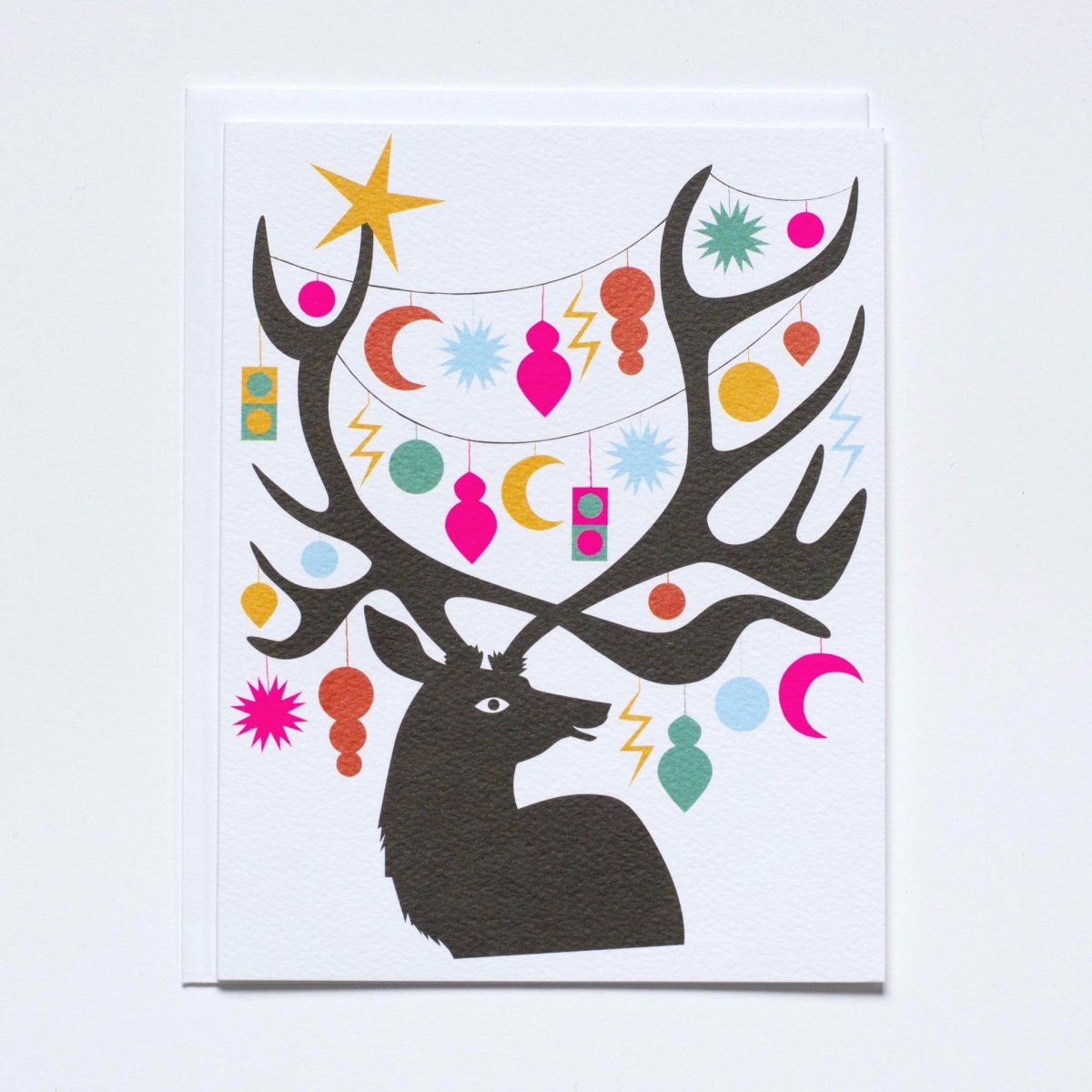 A deer with ornaments in various holiday shapes strung throughout its antlers. Made with recycled paper by Banquet Atelier in Vancouver, British Columbia, Canada.
