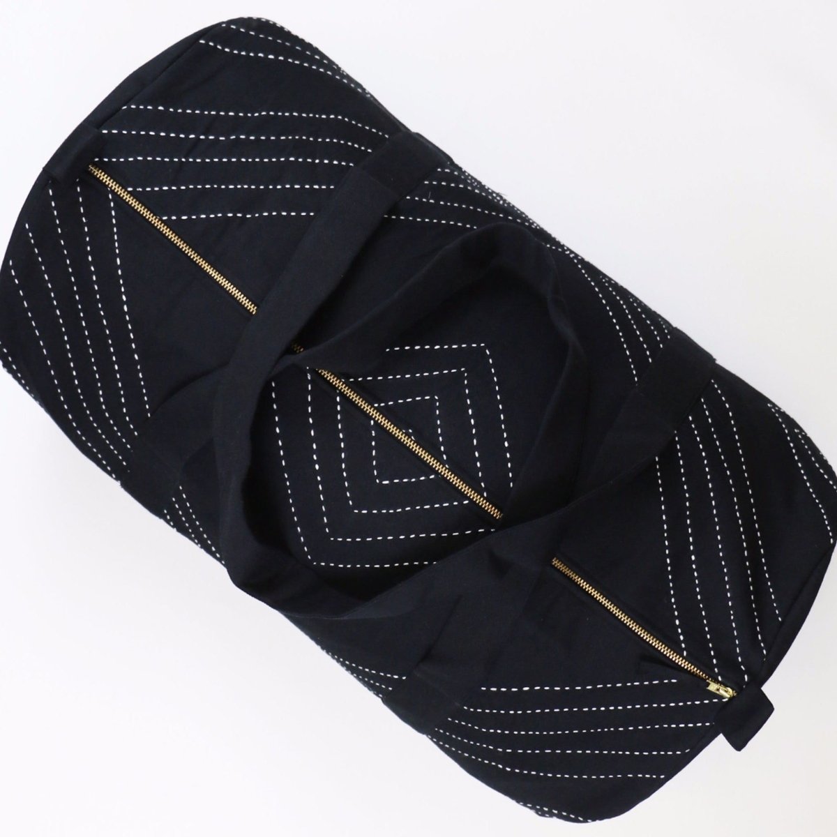 Black duffel bag with white stitched geometric design. Designed by Anchal in Louisville, Kentucky and made in Ajmer, India.