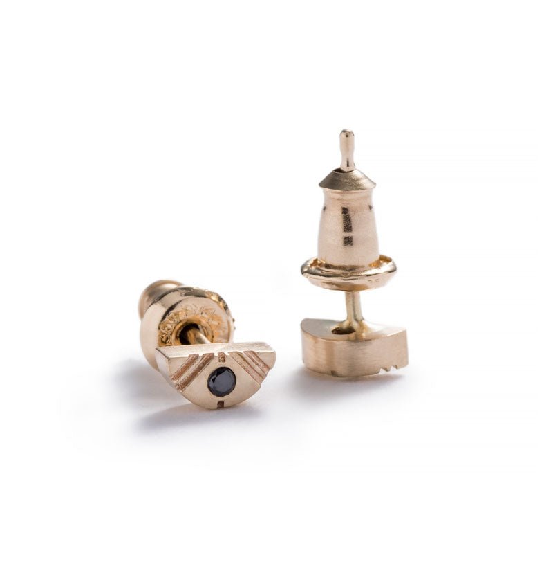Tiny, half-moon stud earrings of 14k yellow gold with round, black diamond inlays, 14k gold earring posts, and 14k gold ear nuts. Hand-crafted in Portland, Oregon.
