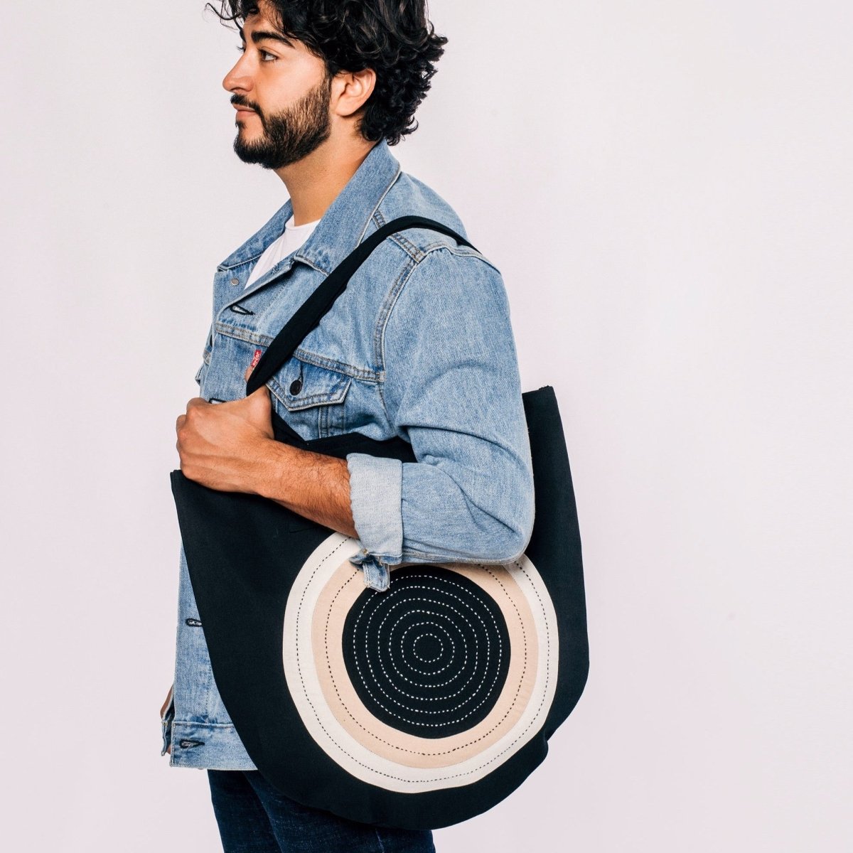 Model holds black tote with cross-stitched circular pattern. Designed by Anchal and handmade in Ajmer, India.