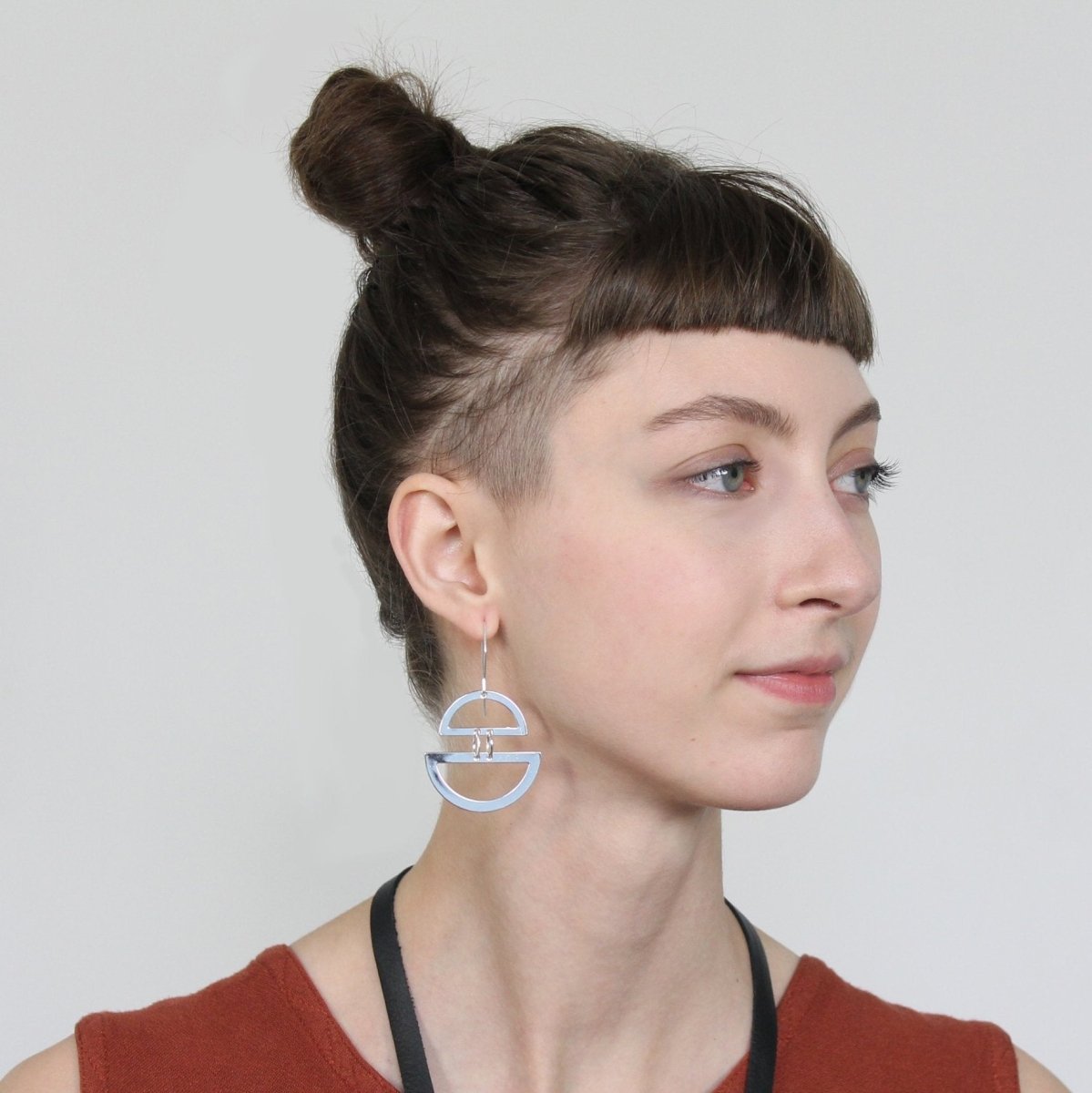 Betsy & iya Elska earrings in sterling silver, styled on a model with a sienna tank top and black leather and polished brass betsy & iya Lumiko necklace.