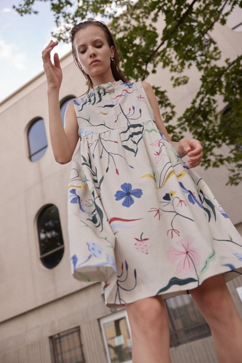 A sleeveless dress with a rouche neckline adorned with blue, yellow, green, pink and red garden illustrations. The Gale Dress in Color is designed and made by Eve Gravel in Montreal, Canada.
