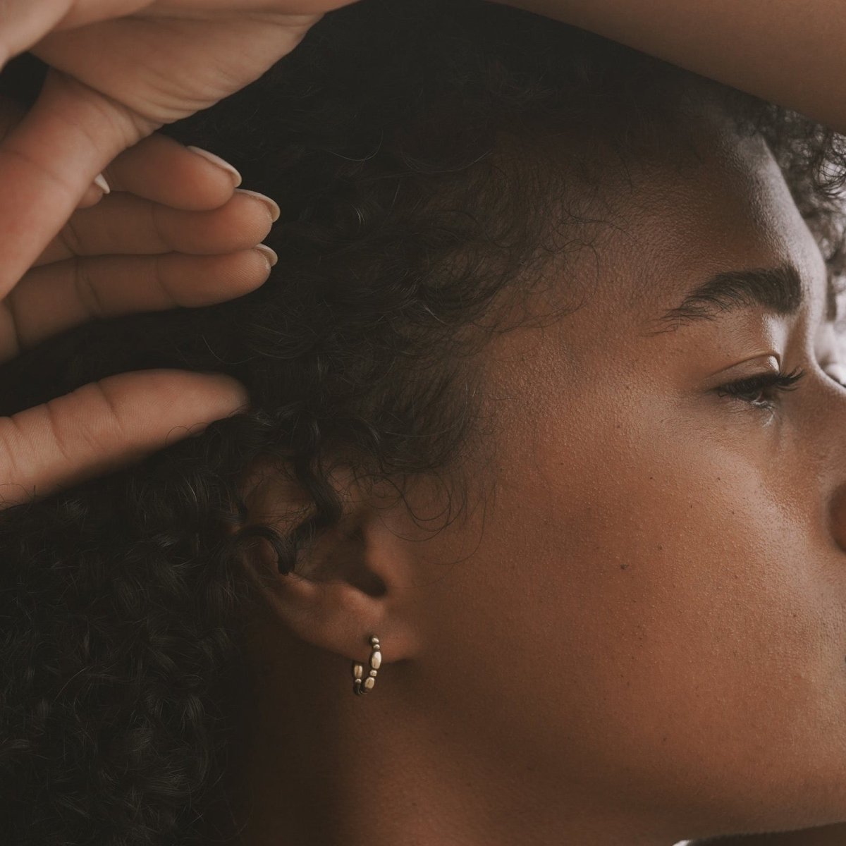 A gold tone hoop connected by circular and oval shapes. The Garden Hoop in designed and handcrafted by Natalie Joy in Portland, Oregon.