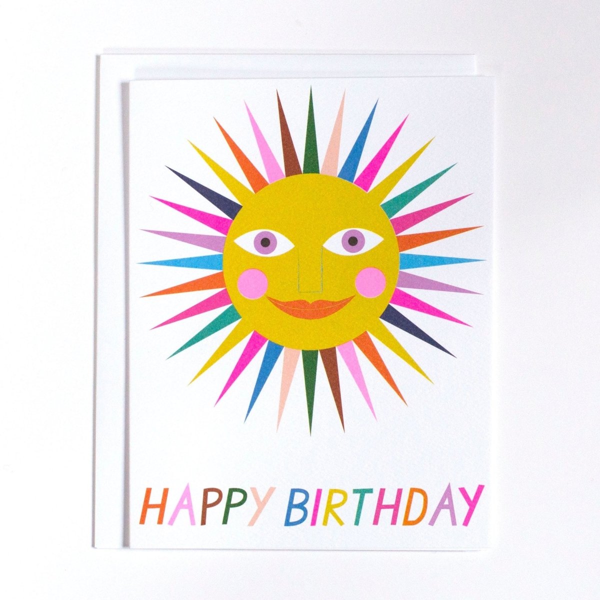 White card shows image of a multicolored smiling sun. Card reads: "Happy Birthday." Made with recycled paper by Banquet Atelier in Vancouver, British Columbia, Canada.