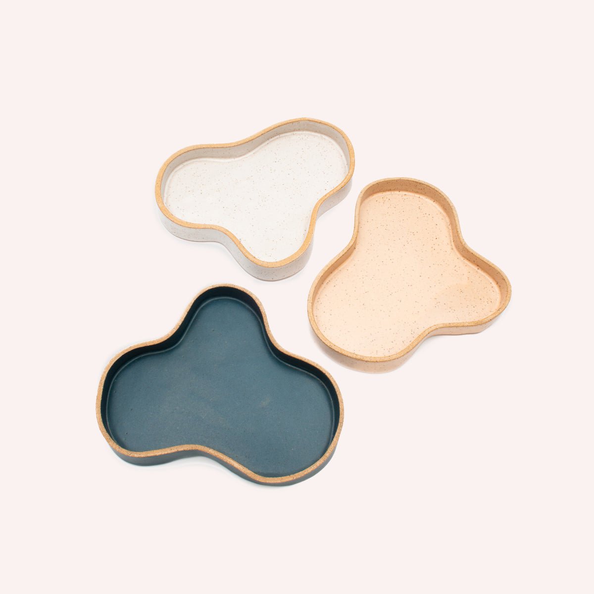 Three Blob Trays centered on a white background. From clockwise: white, pink and blue. The Blob Trays are designed and handmade by Kohai Ceramics in Portland, OR.