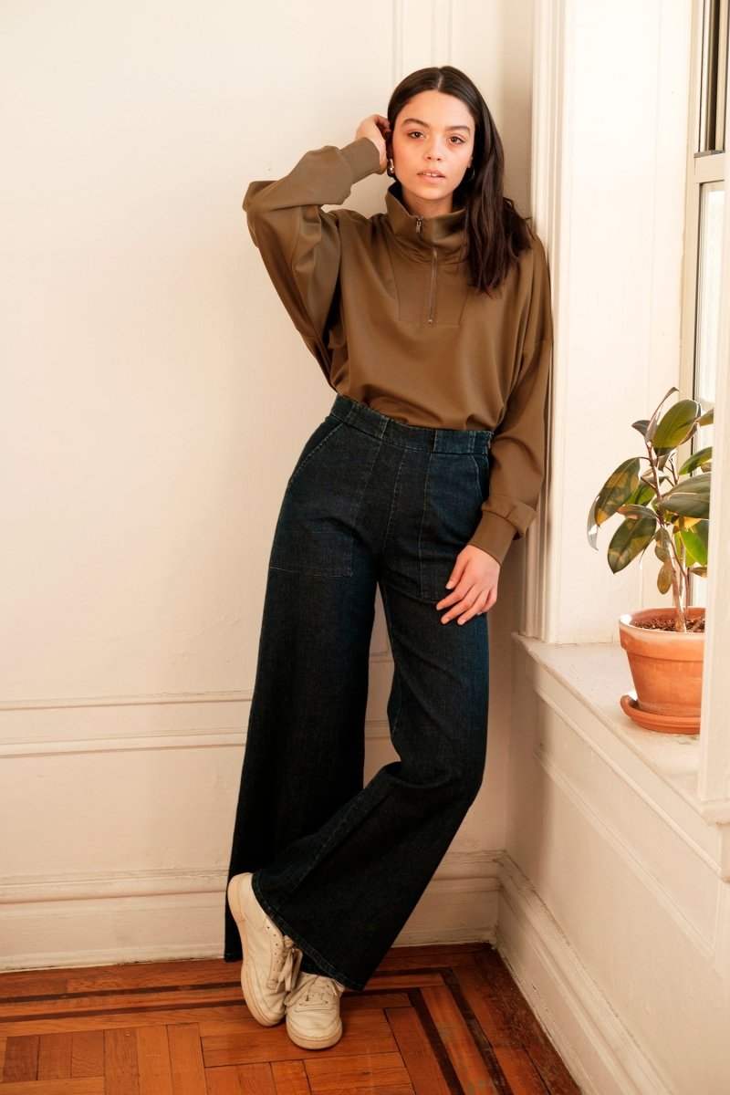 A model wears long wide legged denim pants with large front pockets. The Long Sabrina Jeans in Dark Indigo are designed by Loup and made in New York City, USA.