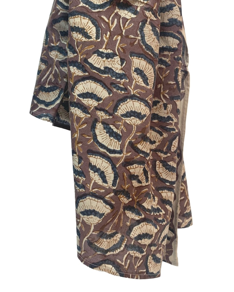 A brown scarf hangs against a white background. The scarf has a floral print pattern in cream and dark grey. The Oversized Scarf in Lena is from designer Maelu.