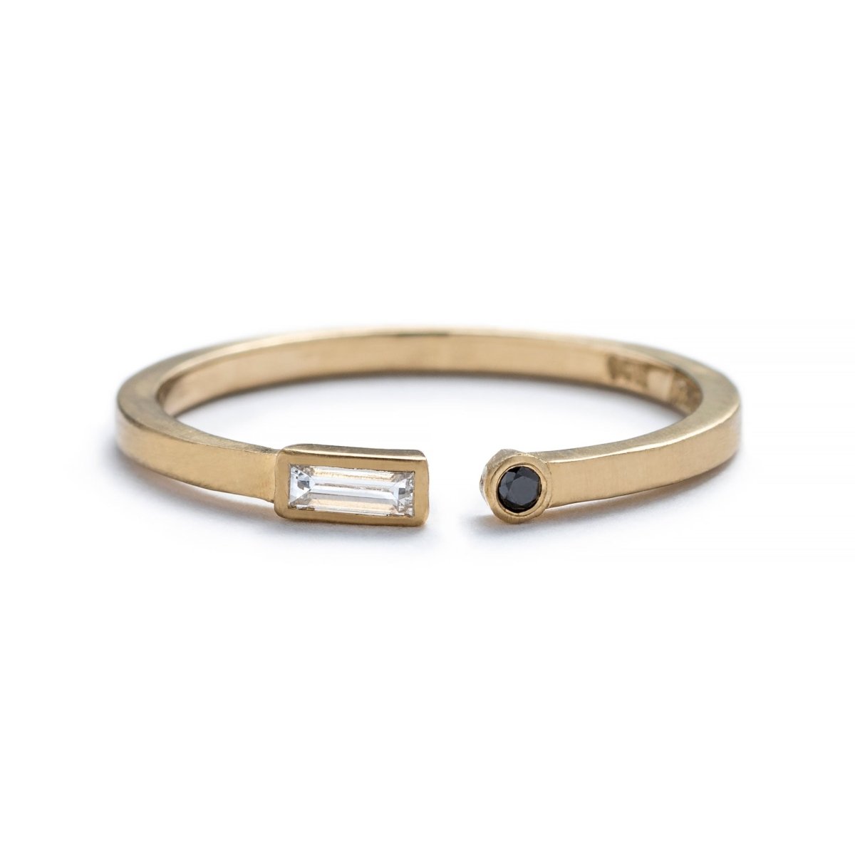 Thin, 14k yellow gold adjustable ring with a matte finish, bezel-set with a small, white diamond baguette on one end, and a small, black, round diamond on the opposite end. Hand-crafted in Portland, Oregon.