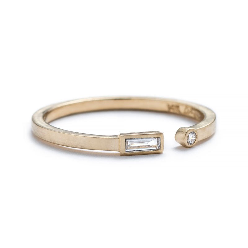 Thin, 14k yellow gold adjustable ring with a matte finish, bezel-set with a small, white diamond baguette on one end, and a small, round, white diamond on the opposite end, with the betsy & iya logo engraved inside the band. Hand-crafted in Portland, Oregon.