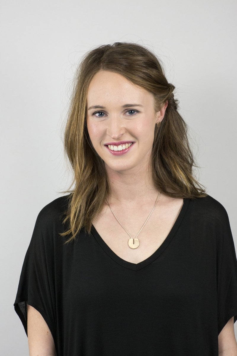 The short version of the cast-bronze and sterling silver Ayni necklace, worn by a smiling model with a black top.