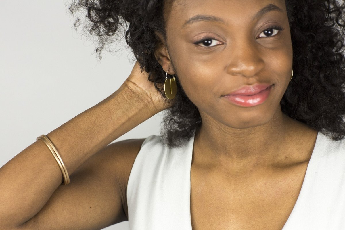 Striking, yet lightweight, mini Lié hoop earrings, worn on a smiling model with two bronze betsy & iya Juntos bangles.