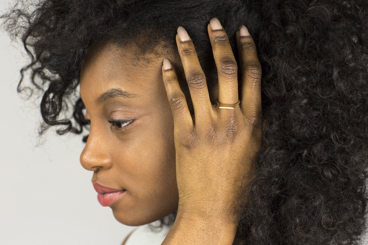 Contemporary and minimal bronze Tuyo ring, worn alone on the middle finger of a model.