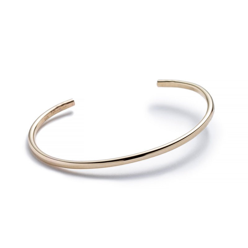 Minimalist, thin, and adjustable stacking cuff of 10k yellow gold , with the Betsy & Iya logo stamped on the inside. Hand-crafted in Portland, Oregon.