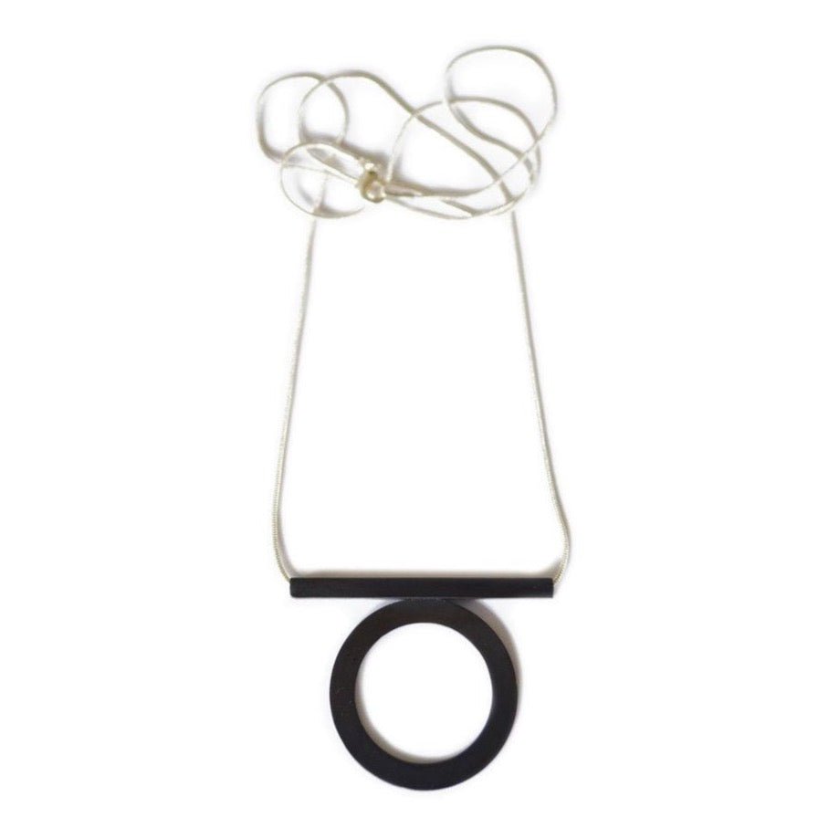 Fabricated oxidized brass circle attached to horizontal bar on a silver plated snake chain. Designed by Natalie Joy and made in Portland, OR.