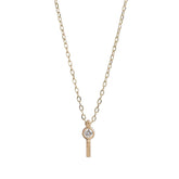 Tiny, ankh-shaped pendant of 14k yellow gold, topped with a round, bezel-set white diamond, and threaded with a delicate gold chain. Hand-crafted in Portland, Oregon.