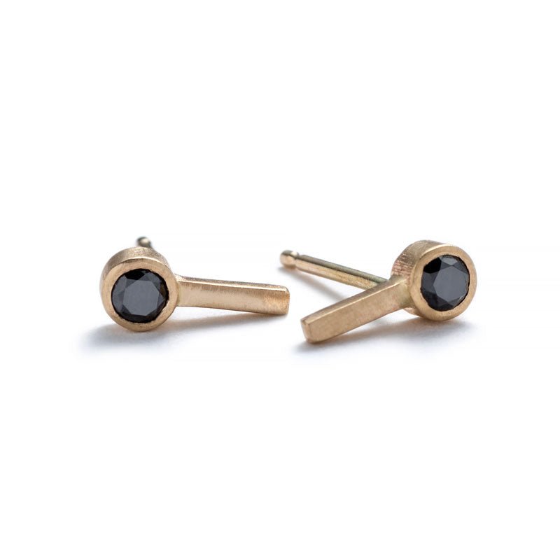 Tiny, ankh-shaped stud earrings of 14k yellow gold, topped with round, bezel-set black diamonds, and finished with 14k gold earring posts. Hand-crafted in Portland, Oregon.
