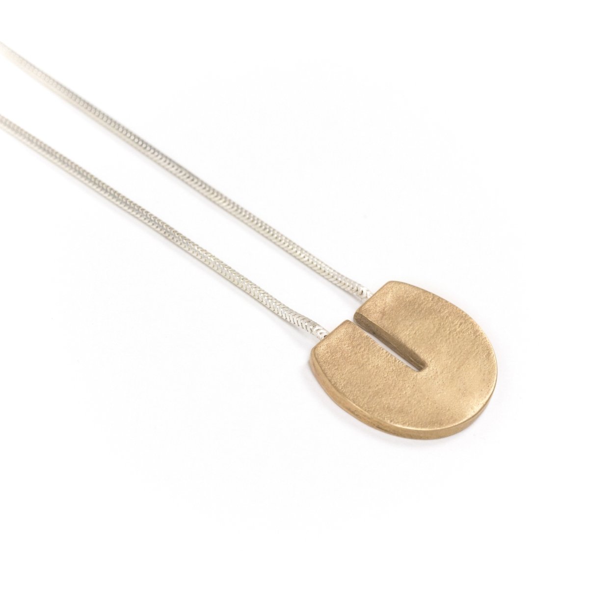 Circular, cast-bronze pendant with a flat top and rectangular cutout that starts at the top and runs halfway through the center of the circle, threaded through the back of the pendant with a sterling silver snake chain. Hand-crafted in Portland, Oregon.