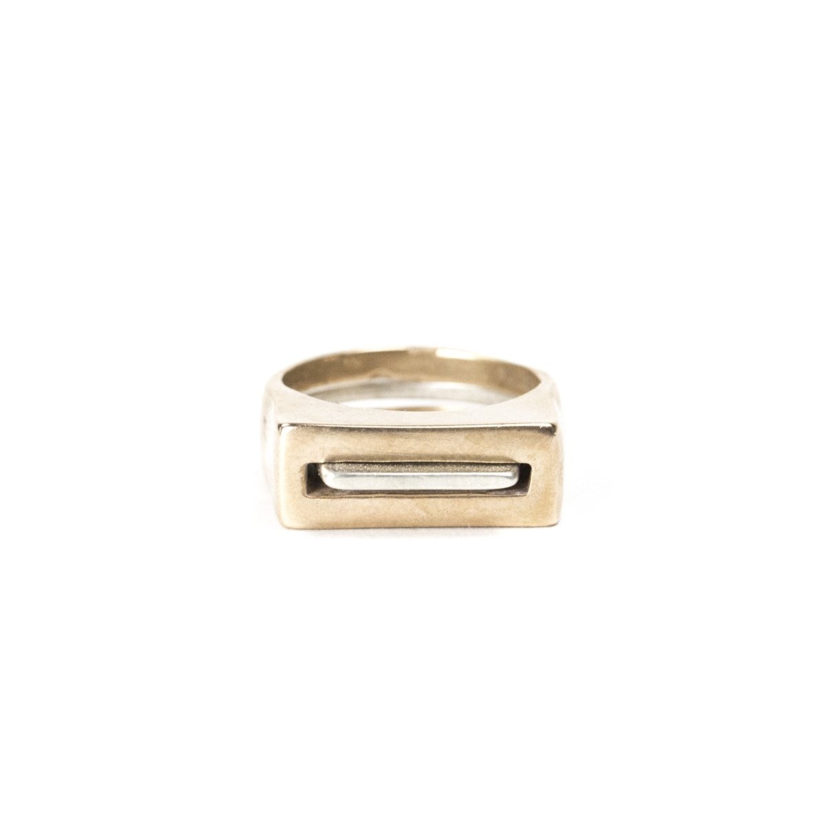 A pair of contemporary rings, featuring one thin, silver ring with an elongated curve (Tuyo) fitted through a chunky, bronze ring with a rectangular cutout (Mía). Hand-crafted in Portland, Oregon.