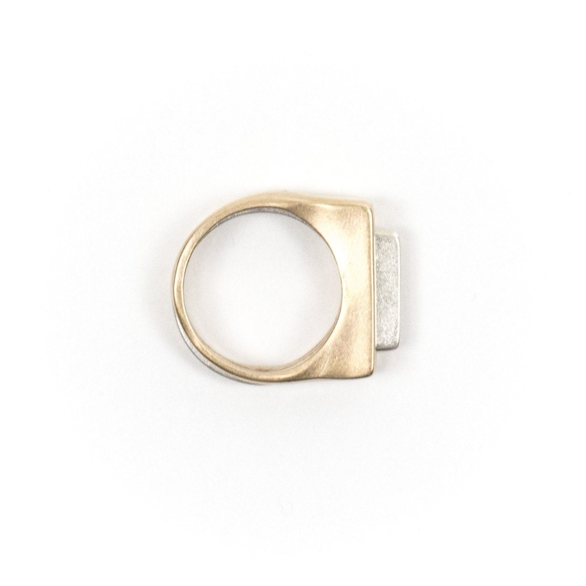 A pair of contemporary rings, featuring one thin, silver ring with an elongated curve fitted through a chunky, bronze ring with a rectangular cutout. Hand-crafted in Portland, Oregon.