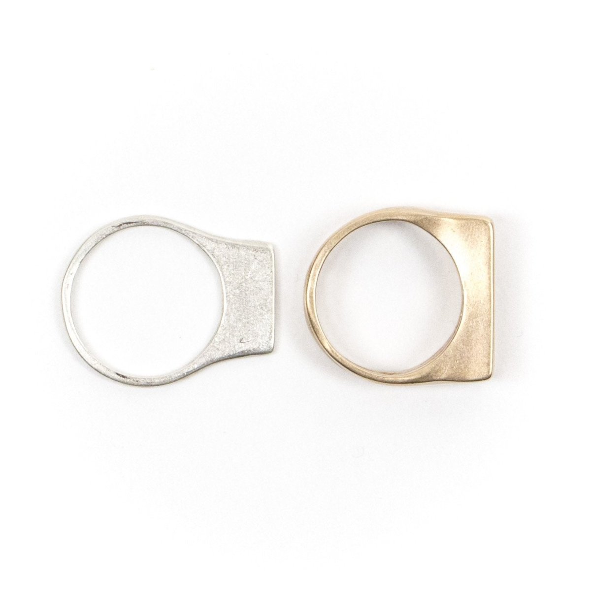 A cast-silver betsy & iya Tuyo ring and a cast-bronze betsy & iya Mía ring, pictured side by side. Hand-crafted in Portland, Oregon.