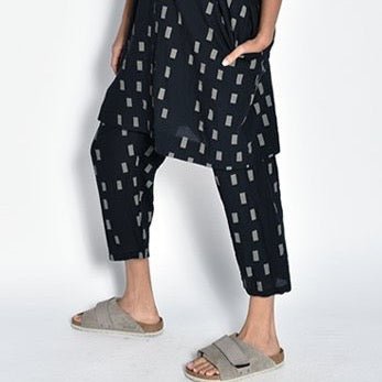A model wears a loose fitting cropped straight leg black pant with an off-white square pattern. The Pants in Black Disko are designed and sewn by UZI NYC in Brooklyn, New York.
