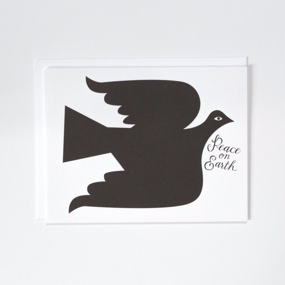 A black dove against a white background with the message: "PEACE ON EARTH." Made with recycled paper by Banquet Atelier in Vancouver, British Columbia, Canada.