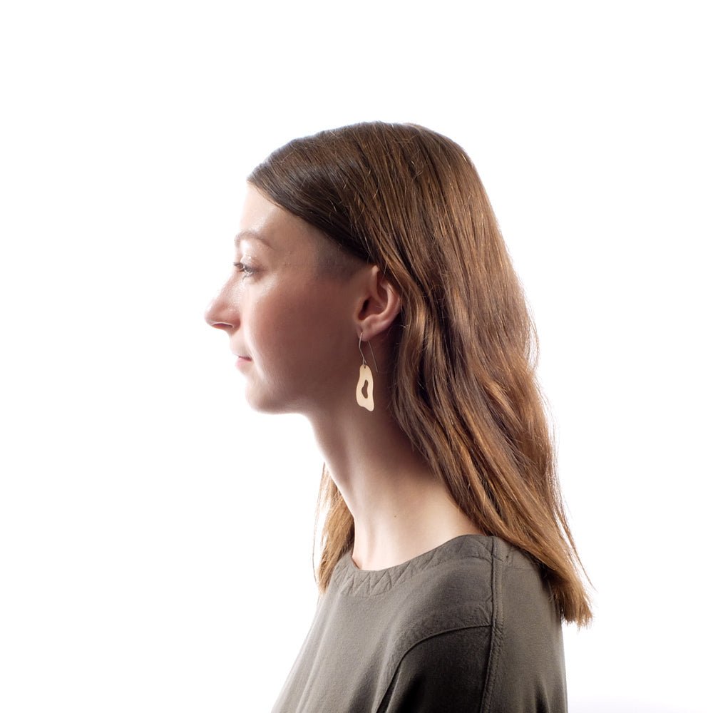Bronze betsy & iya Pasu dangle earrings, pictured on the profile of a model with long, golden brown hair.