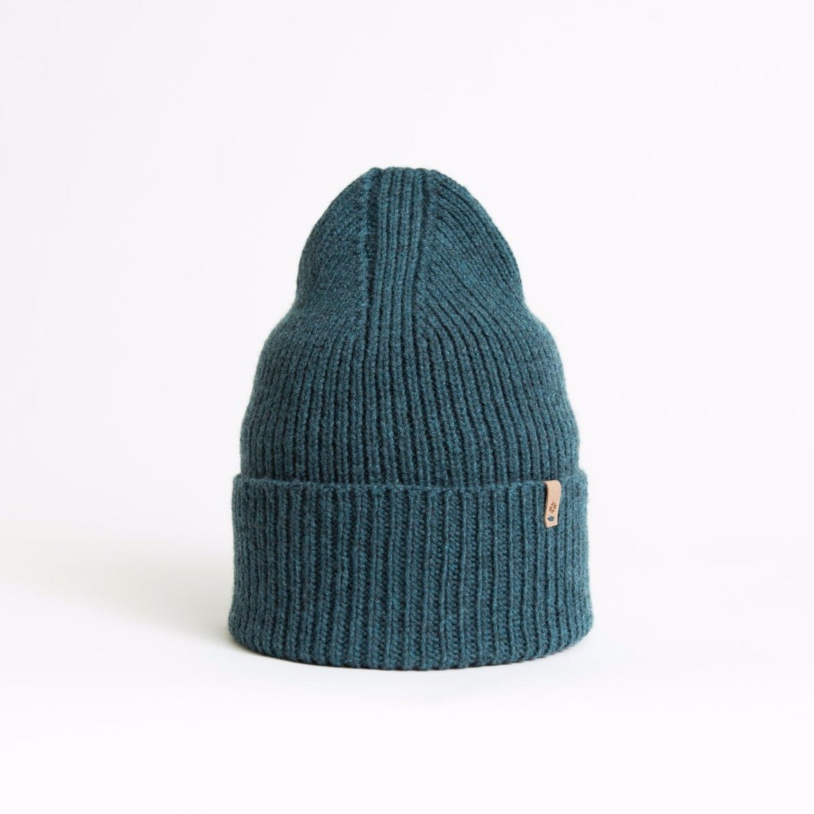 Blue/green knitted and cuffed hat with a decrease detail on top. The Merino Rib hat in Dragonfly Green is designed by Dinadi and hand knitted in Kathmandu, Nepal.