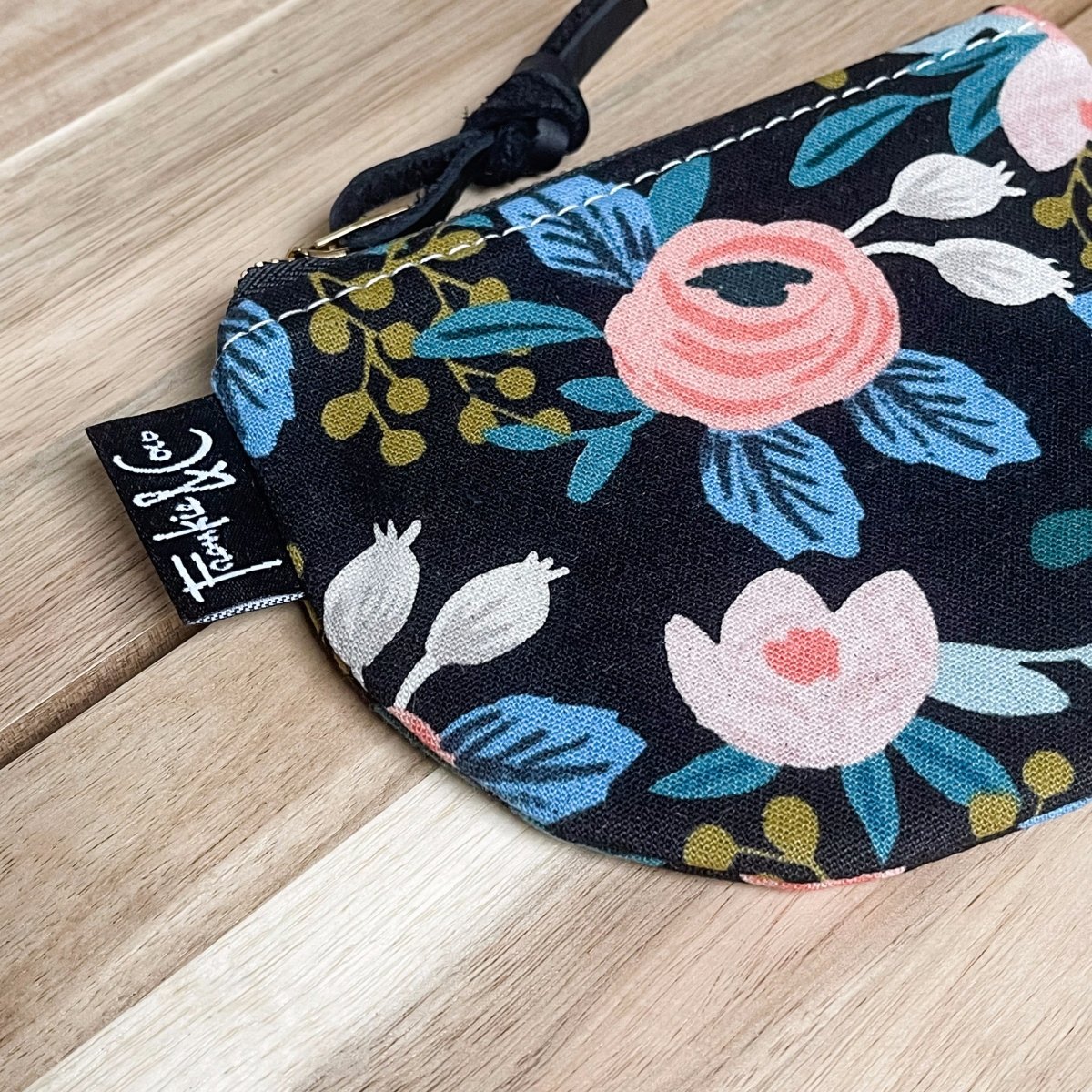 A black canvas half moon shaped pouch with a black and floral pattern and zipper pull. The Richmond Half Moon Pouch in Dark Roses is designed and handmade by Frankie & Coco in Portland, OR.