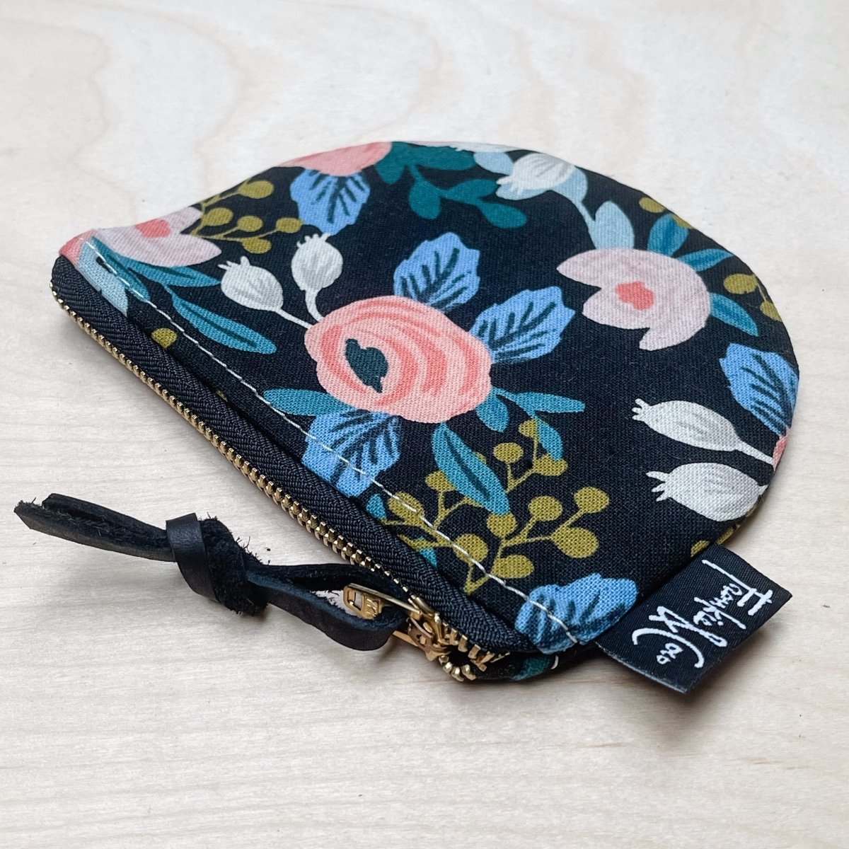 A black canvas half moon shaped pouch with a black and floral pattern and zipper pull. The Richmond Half Moon Pouch in Dark Roses is designed and handmade by Frankie & Coco in Portland, OR.