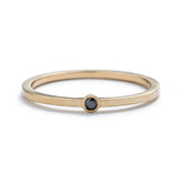 Thin, 14k yellow gold band with a matte finish, featuring a small, round, bezel-set black diamond. Hand-crafted in Portland, Oregon.