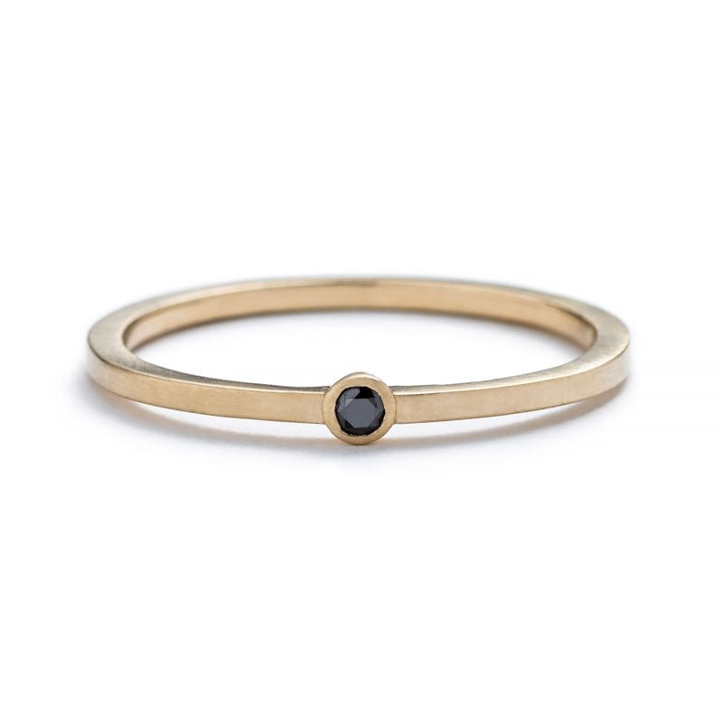 Thin, 14k yellow gold band with a matte finish, featuring a small, round, bezel-set black diamond. Hand-crafted in Portland, Oregon.