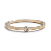 Thin, 14k yellow gold band with a matte finish, featuring a small, round, bezel-set white diamond. Hand-crafted in Portland, Oregon.