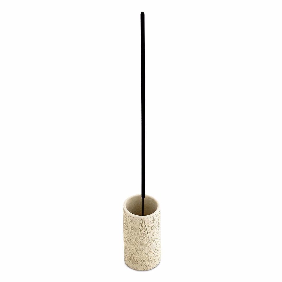 Cream colored cylindrical incense burner with an external embossed pattern. Holds a single stick of incense. Made by Skeem Design in Philadelphia, PA.