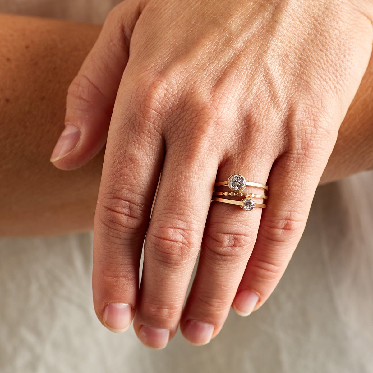 Model wears the Itero ring in a stack between two Sano rings.